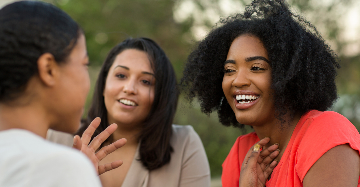 Three women in conversation, smiling and listening to each other
